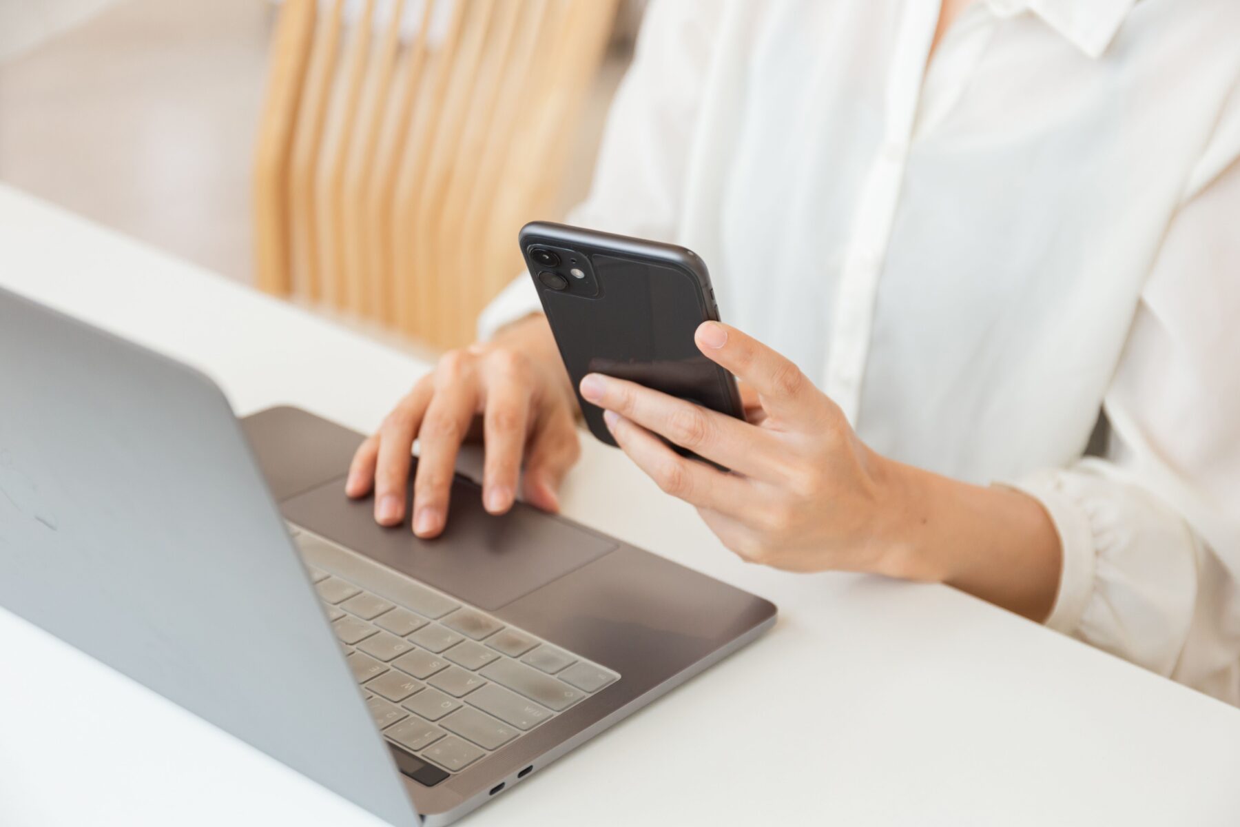 lady holding a phone and typing on a computer at the same time