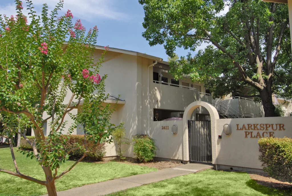 Property entrance gate with big trees and lush landscaping