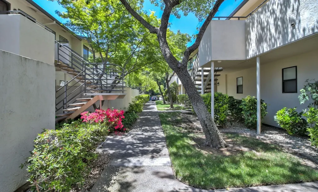 Green space between residential buildings with big trees and lush landscaping
